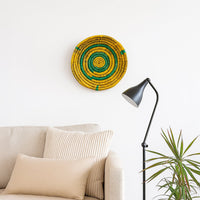 Colorful woven wall basket displayed above sofa with floor lamp and plant adding artistic texture to cozy interior Decor space.