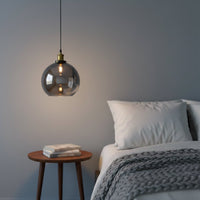 Smoked glass pendant light beside bed with warm ambient glow adding modern elegance and cozy bedroom decor appeal.