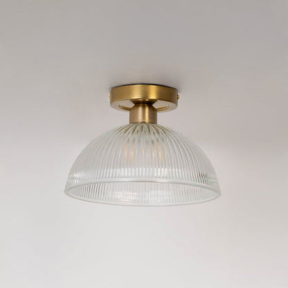 Ceiling light with brushed gold holder and ribbed clear glass dome shade shown switched off on plain white background.
