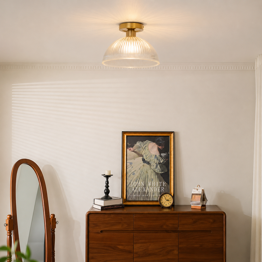 A ceiling-mounted light fixture with a ribbed clear glass shade and a gold-toned brass ceiling mount, shown installed in a styled room above a wooden console table.