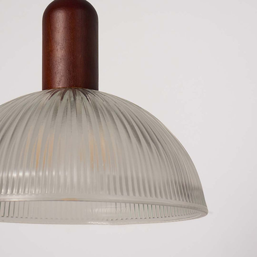 Closeup of ribbed clear glass and walnut wood pendant light highlighting refined craftsmanship.