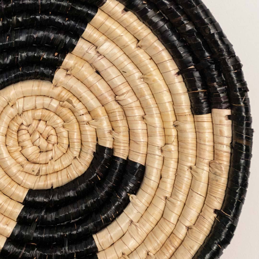 Closeup view of handcrafted black cream woven seagrass wall basket with abstract block pattern for bohemian wall decor.