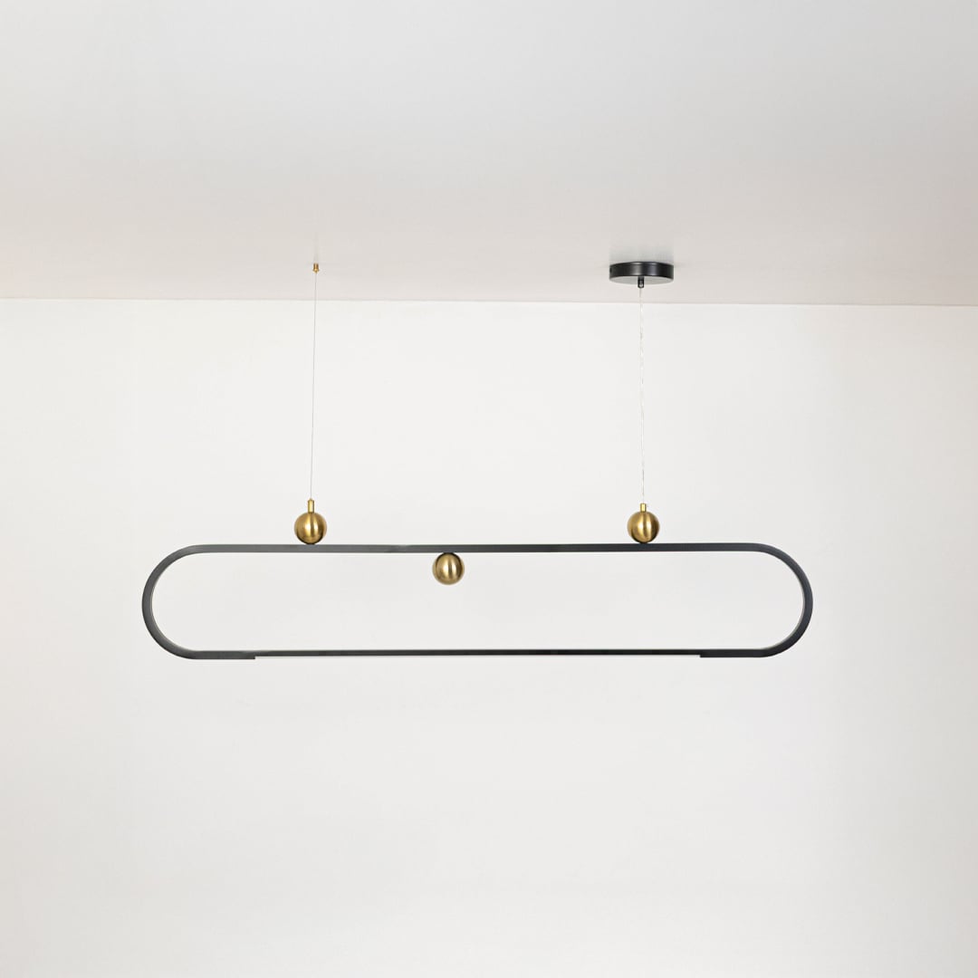 Chandelier shown on a plain white background with lights off highlighting its slim oval frame and gold decorative spheres.
