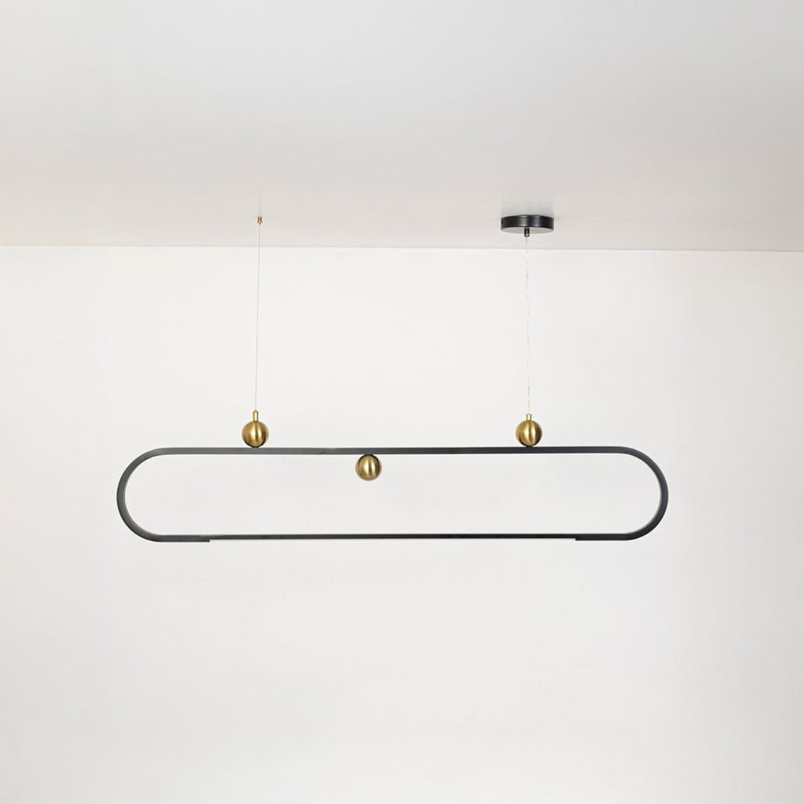 Chandelier shown on a plain white background with lights off highlighting its slim oval frame and gold decorative spheres.
