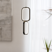 A modern double-light pendant lamp with a black metal frame and glowing white LED light, hanging in a minimalist room setting with a concrete wall and sheer white curtains.