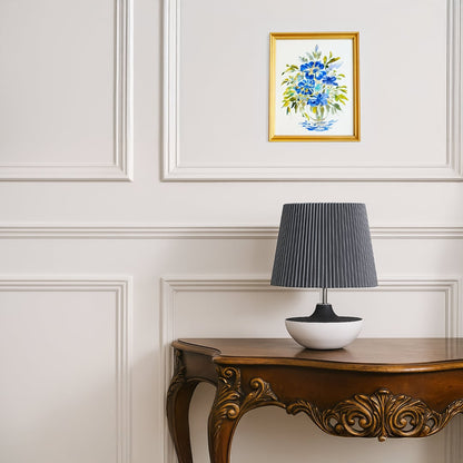 Modern table lamp with a black and white ceramic base and grey pleated shade placed on a carved wooden side table adding a soft contemporary touch to the room.