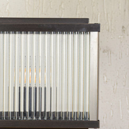 Close view of outdoor wall light with vertical ribbed glass panels and metal frame showcasing durable weather resistant lighting design.