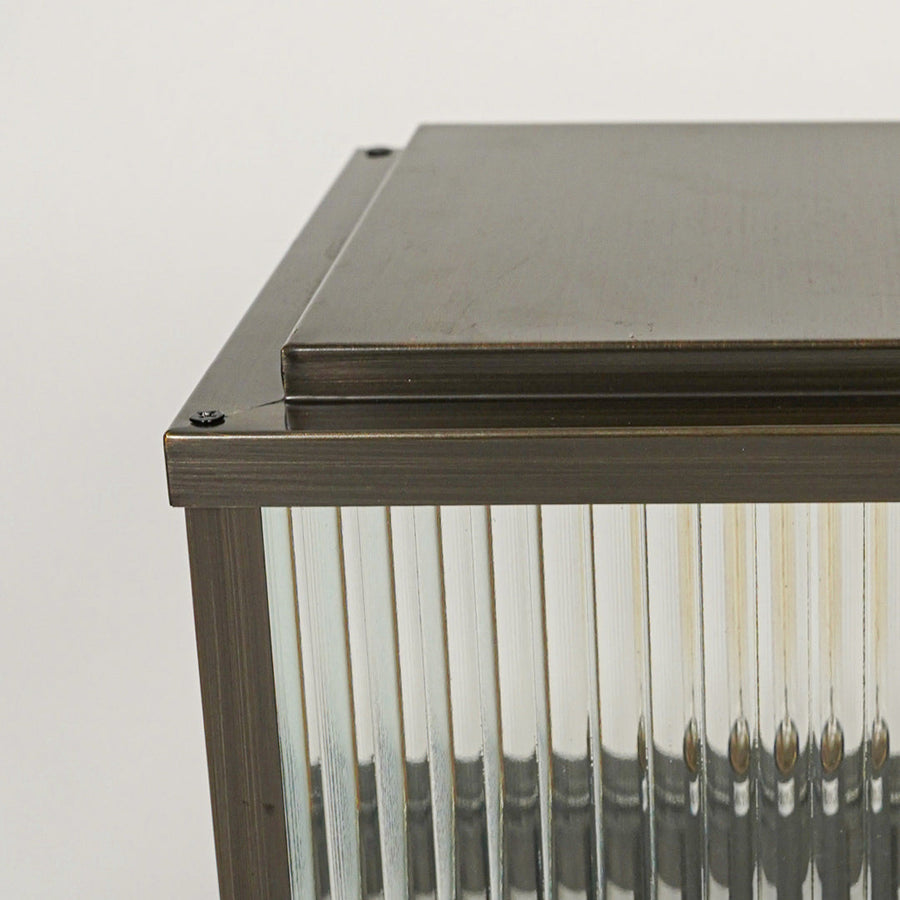 Contemporary exterior wall light with textured glass and metal body creating warm ambient lighting for modern outdoor decor.