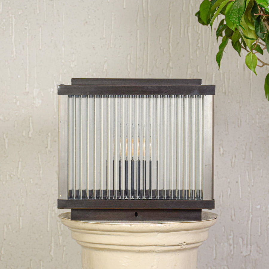 Modern outdoor wall light with rectangular metal frame and ribbed glass shade mounted on exterior wall ideal for patio or garden lighting.