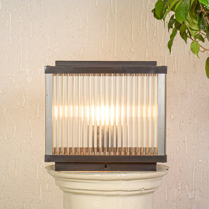 Contemporary outdoor wall light with ribbed glass shade mounted on exterior wall creating soft warm lighting for modern outdoor decor.

