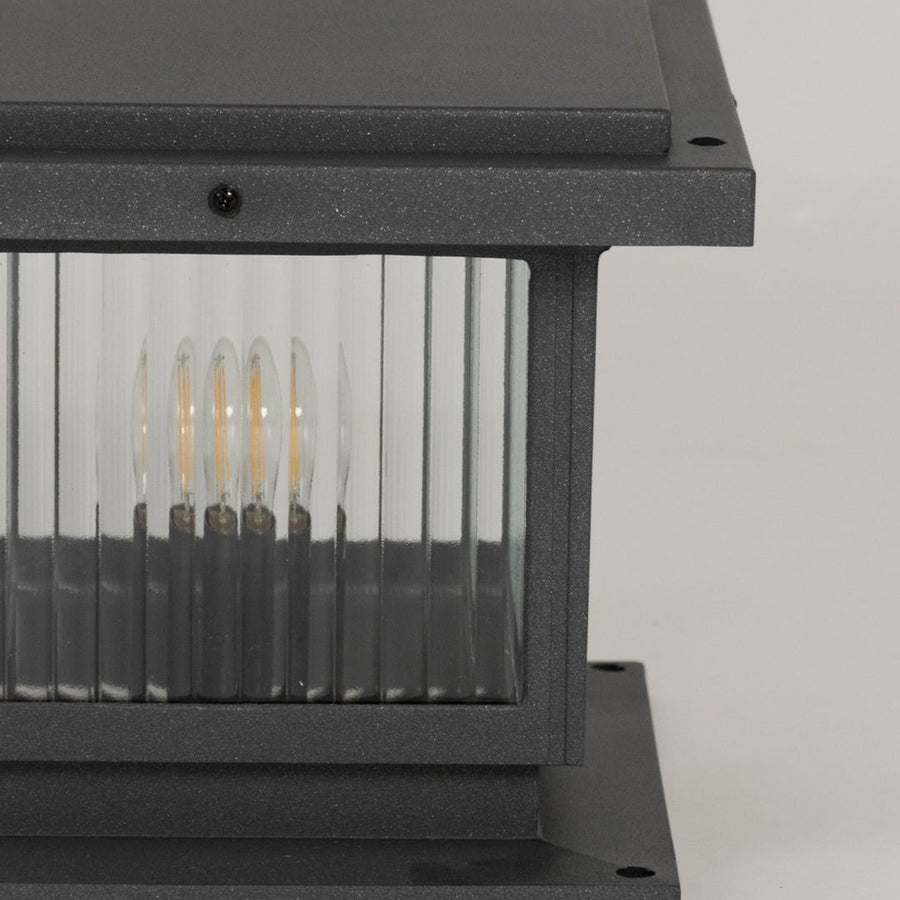 Closeup of black outdoor gate light with ribbed glass panels for elegant exterior decor styling use.