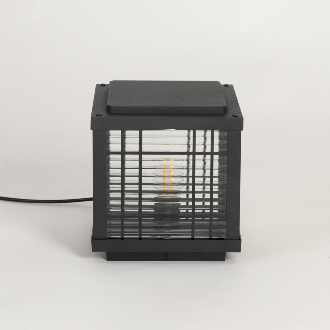 Black outdoor pillar lamp glowing LED through frosted glass ideal for garden patio balcony and modern exterior lighting.