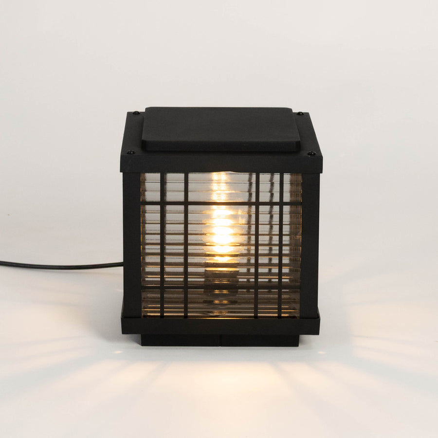 Black outdoor gate light with warm glowing bulb for elegant modern exterior decor styling use.