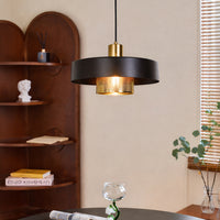 Modern black pendant light with amber glass shade hanging above table for luxury dining room decor styling.
