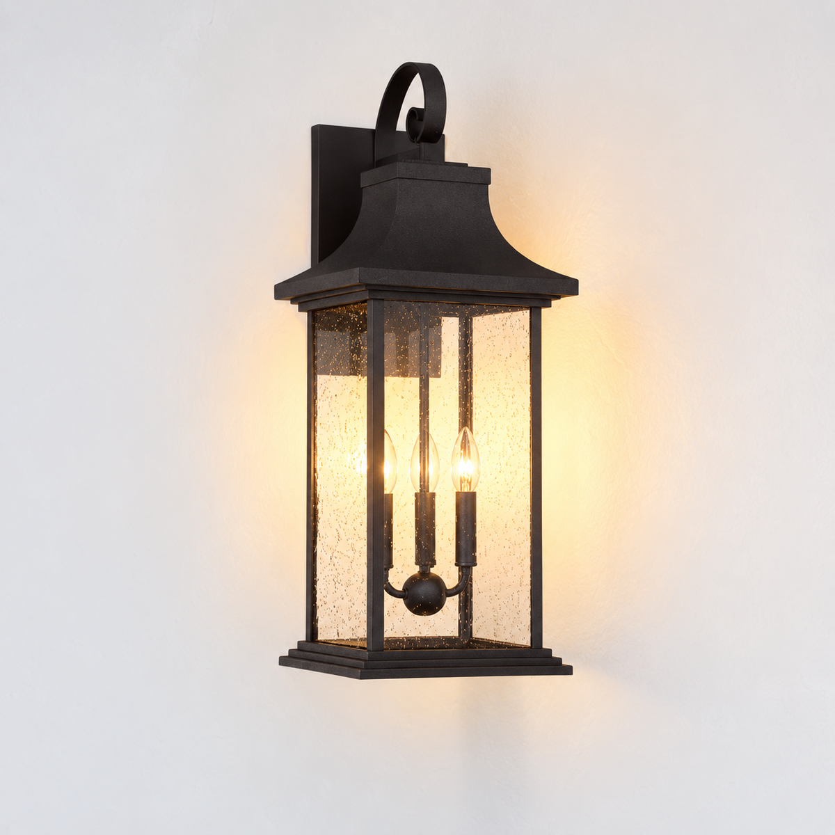 A black outdoor wall sconce with a lantern-style frame and textured glass panels, shown illuminated against a plain white wall.