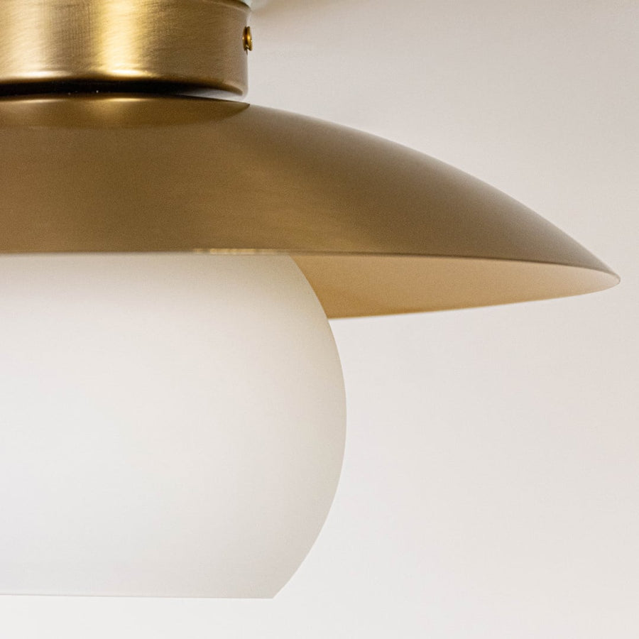 Closeup of ceiling light with brushed gold wide dome shade and frosted glass globe for modern home lighting decor.