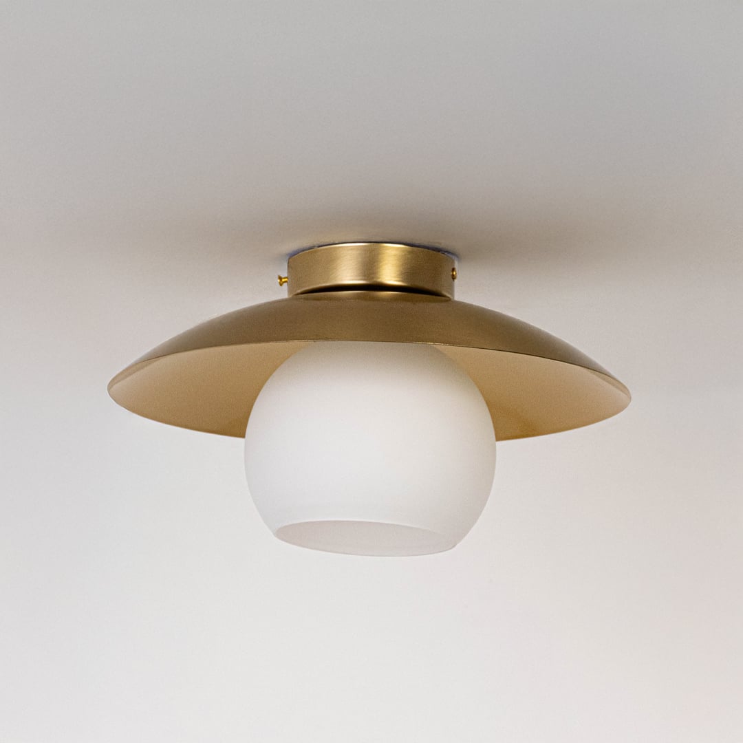 Ceiling light with brushed gold wide dome shade and frosted glass globe shown switched off on plain white background.