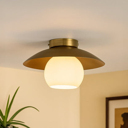 Modern ceiling light with wide brushed gold shade and frosted glass globe styled in living room for warm home lighting.