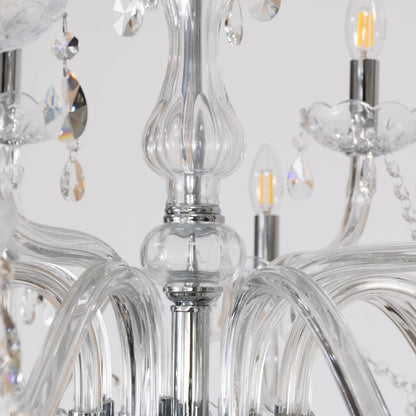 Closeup of crystal chandelier with ornate glass arms candle lights and crystal drops for luxury home decor.