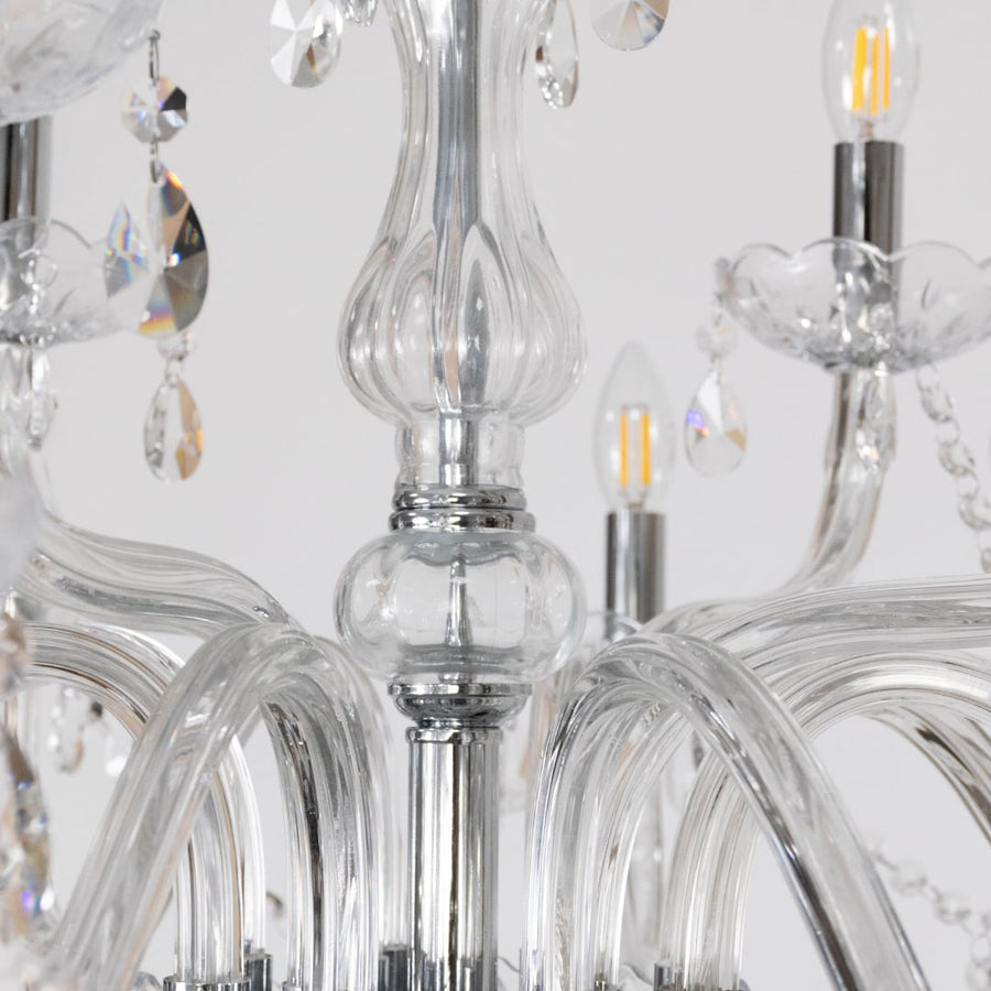 Closeup of crystal chandelier with ornate glass arms candle lights and crystal drops for luxury home decor.