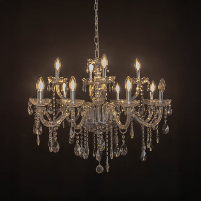 Crystal chandelier with candle lights and hanging crystal drops glowing warmly on black background view.