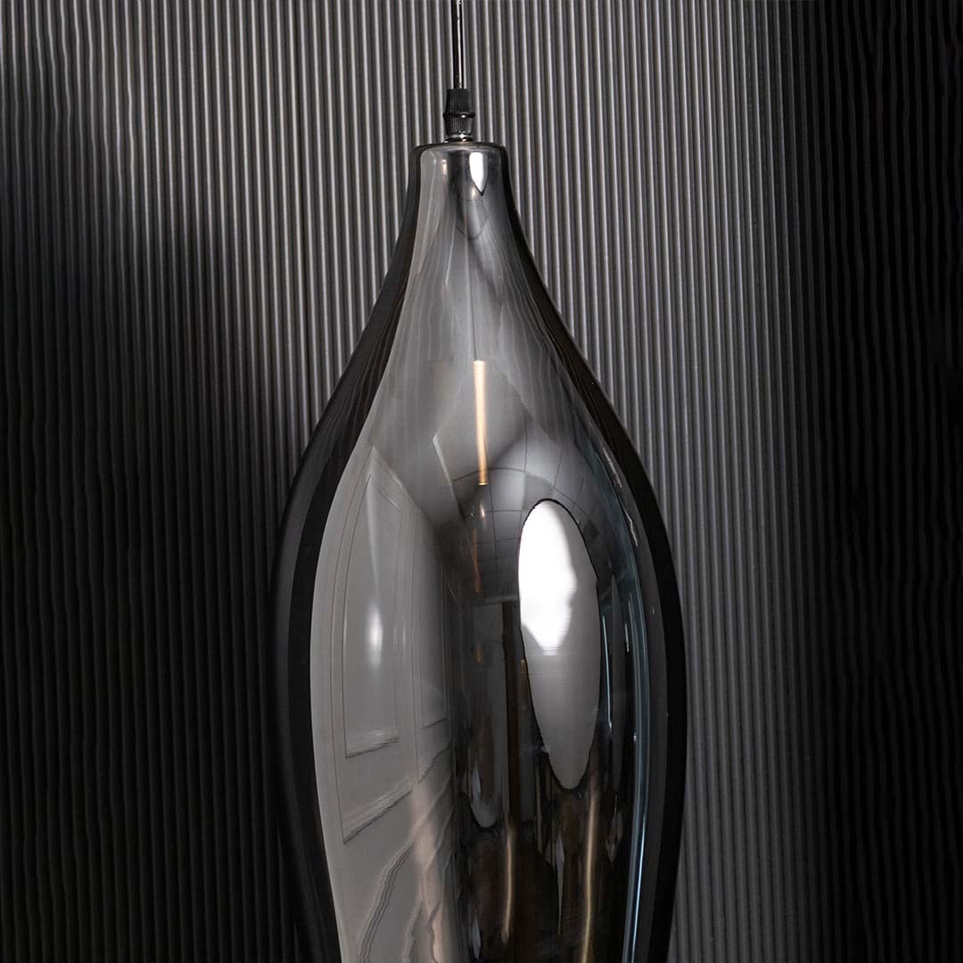 A closeup view of the smoked black pendant light showing the smooth curved glass surface and warm reflective glow ideal for premium interiors.