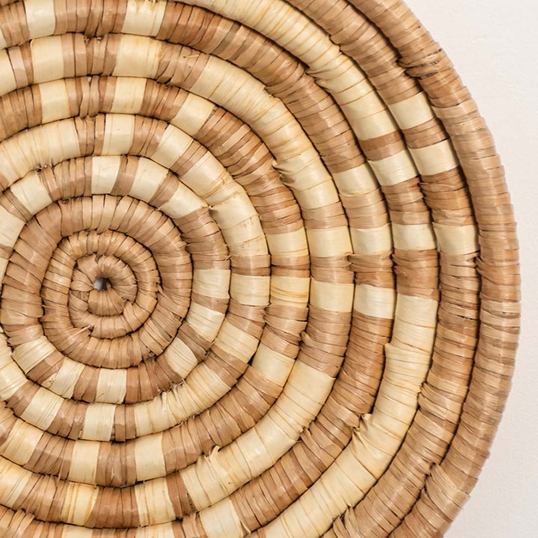 A closeup view of the natural rattan wall decor plate showing its textured spiral weaving and handcrafted rustic finish for warm earthy home decor styling.