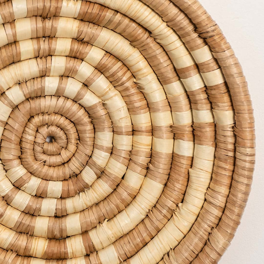 A closeup view of the natural rattan wall decor plate showing its textured spiral weaving and handcrafted rustic finish for warm earthy home decor styling.