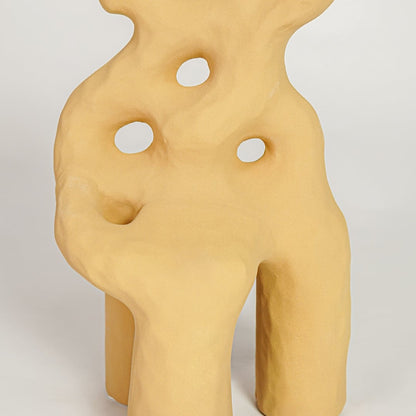 Closeup of mustard glazed ceramic vase with artistic curved silhouette ideal for elegant home decor shelf styling.