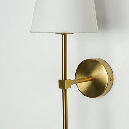 Contemporary wall light in gold metal finish with fabric shade for bedroom or living decor lighting white background.