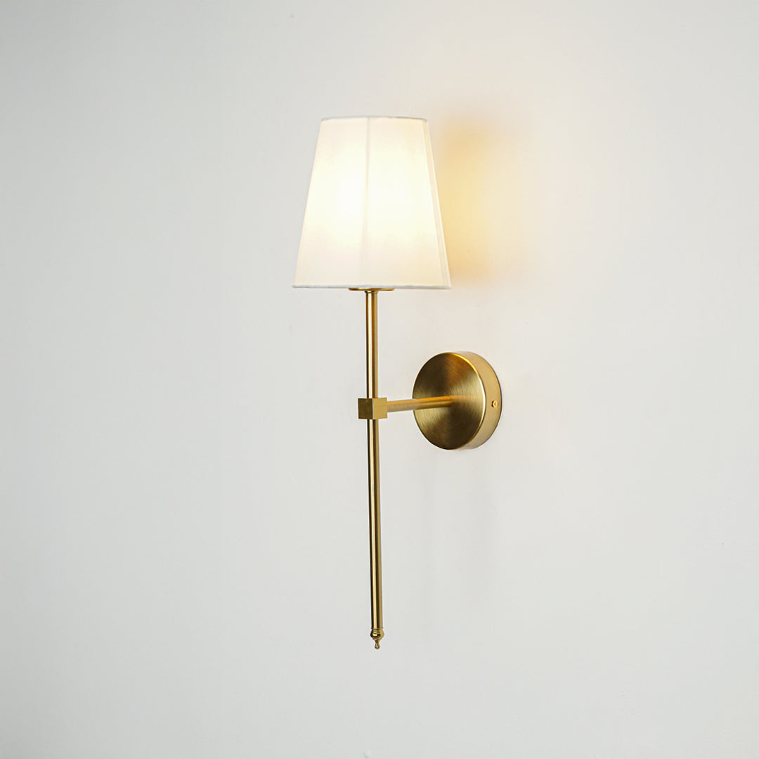 Modern wall light in gold metal finish with fabric shade for bedroom or living room ambient lighting decor white background.