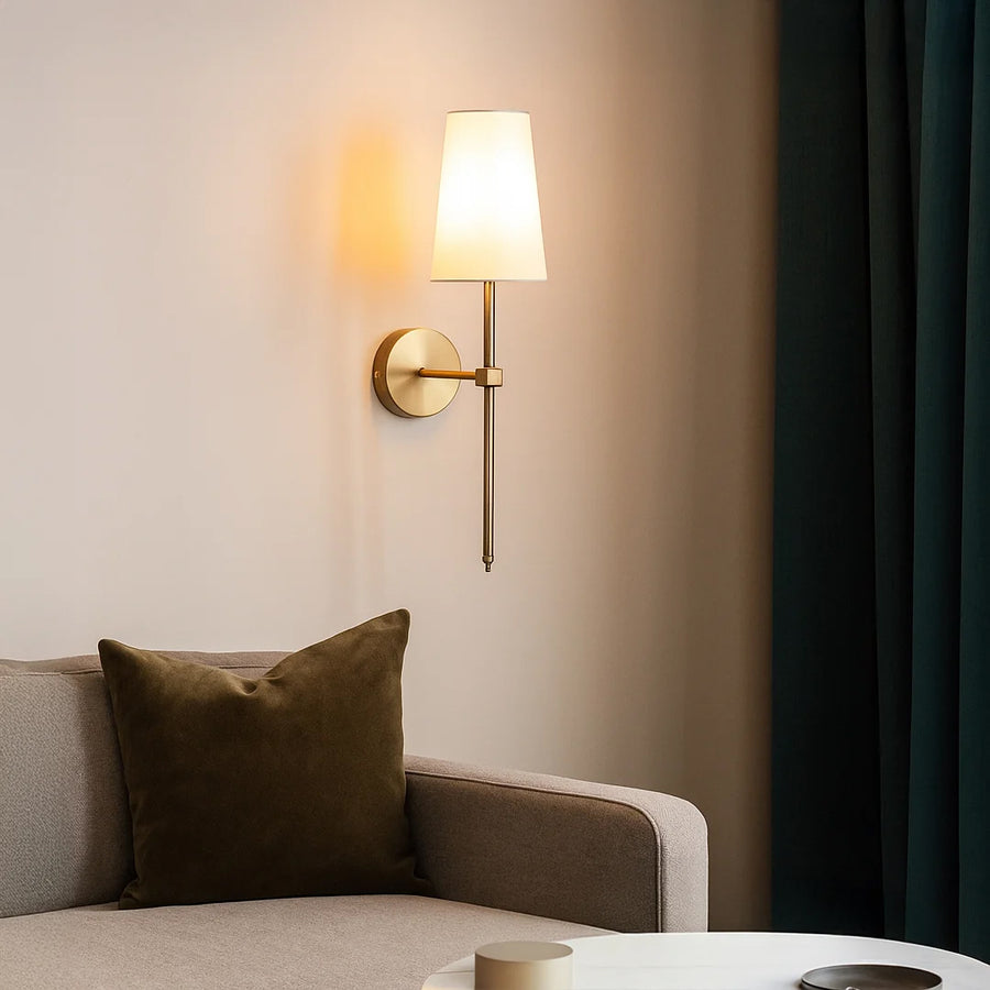 Elegant wall light in gold metal finish with fabric shade for bedroom or living room ambient lighting decor white background.