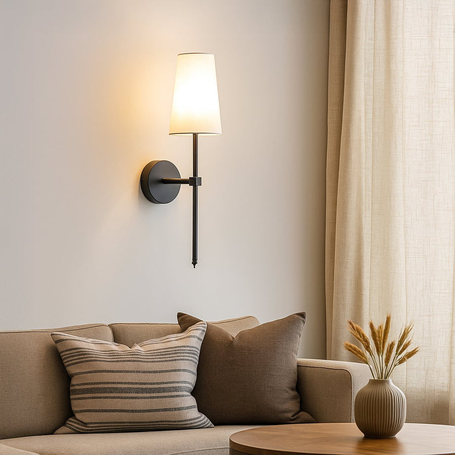 Elegant white fabric drum shade wall sconce with tall black metal rod mounted on interior wall creating refined ambient lighting.