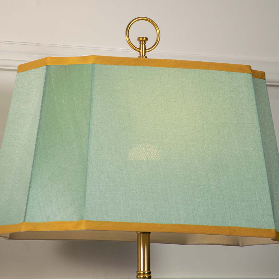 Blue glass table lamp with fabric shade placed on a wooden console table creating refined contemporary lighting.