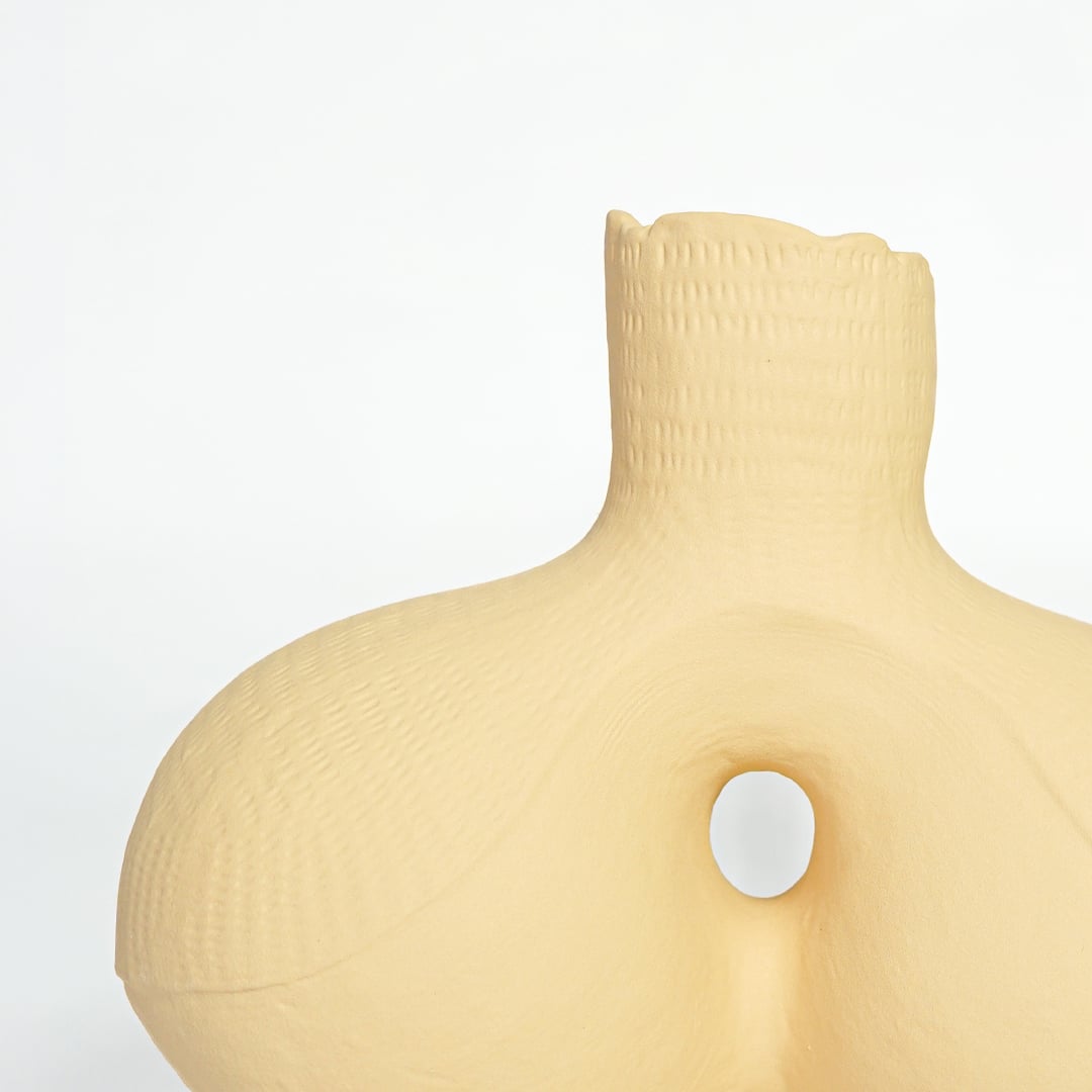 Textured beige ceramic artistic vase with rounded form for elegant console table and office decor.