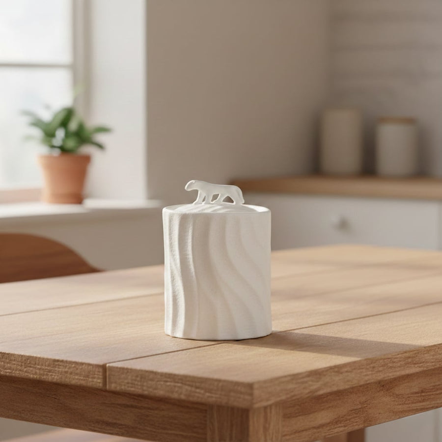 White textured ceramic decorative jar with sculpted animal lid styled on wooden table in warm modern living room setting.