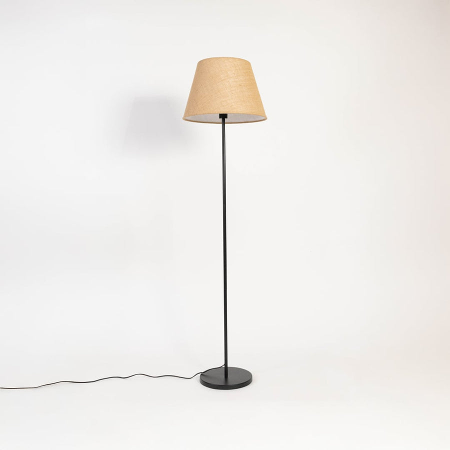 Beige floor lamp with fabric shade and black base displayed turned off against an off-white background.