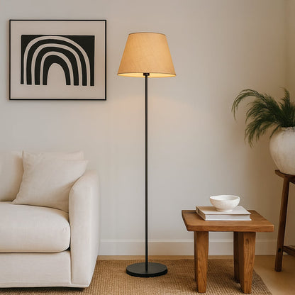 Beige floor lamp with fabric shade styled beside a modern sofa and wooden side table in a cozy living room setup.