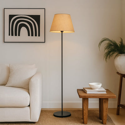 Beige floor lamp with fabric shade styled beside a modern sofa and wooden side table in a cozy living room setup.
