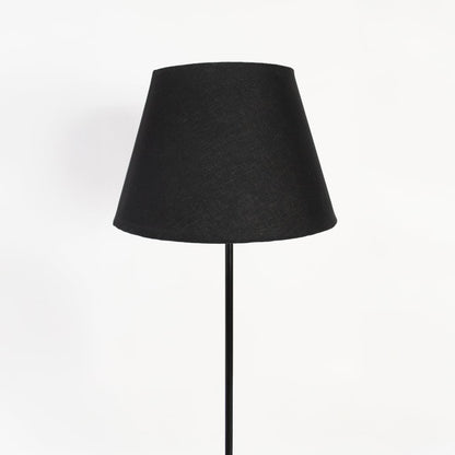 Closeup of black fabric shade and slim metal stand floor lamp for living room or bedroom lighting.