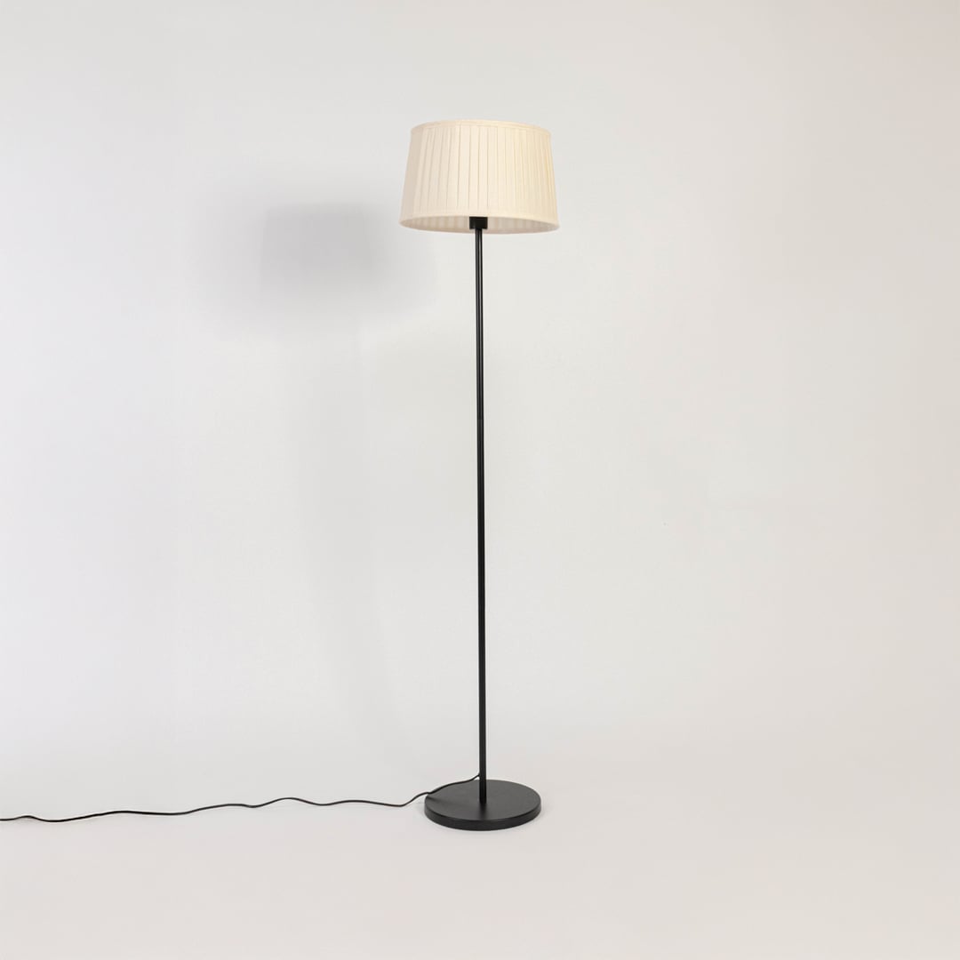 Modern white pleated shade floor lamp with slim black stand shown switched off on plain white background.