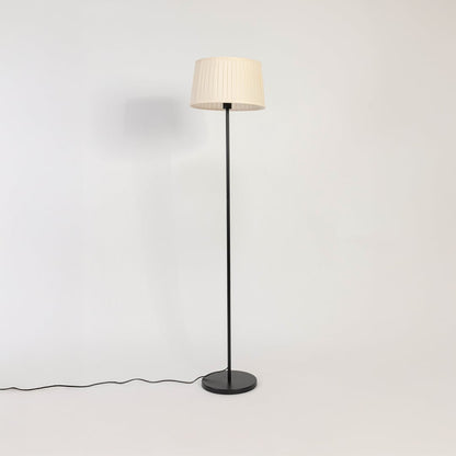 Modern white pleated shade floor lamp with slim black stand shown switched off on plain white background.