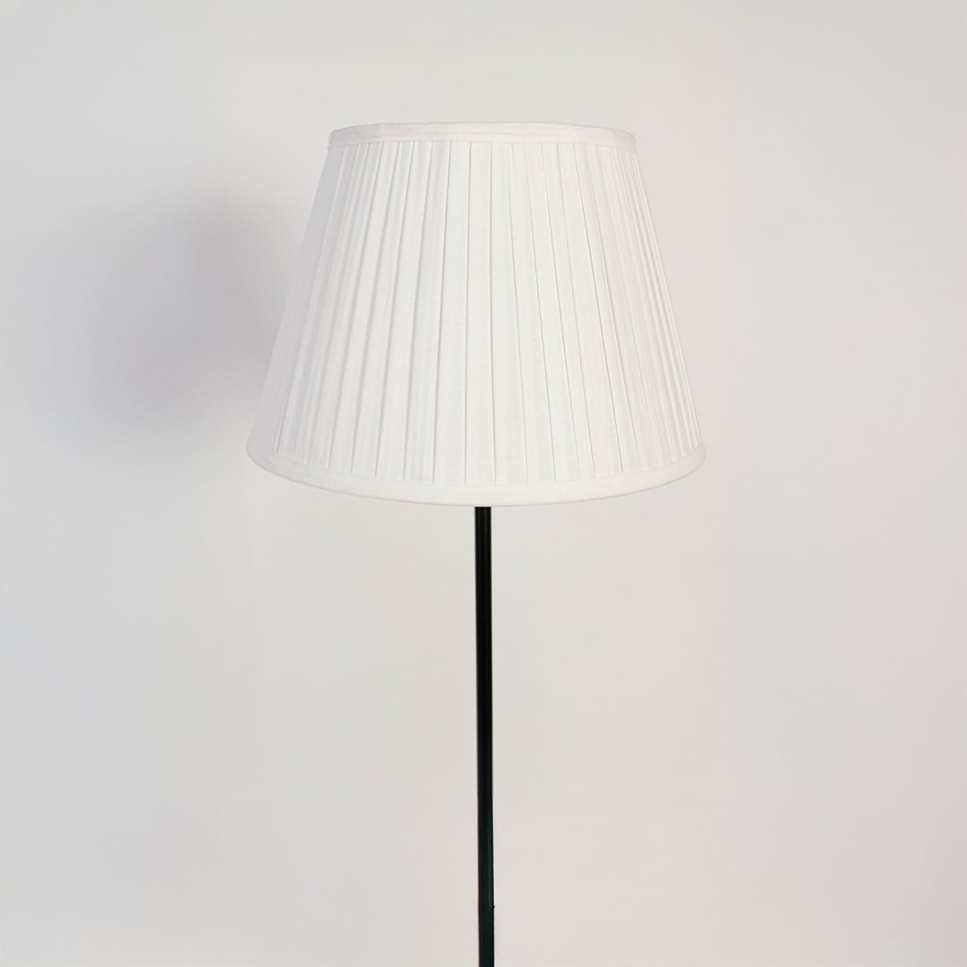 Closeup of pleated fabric floor lamp shade with elegant modern black stand.