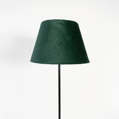 Closeup of dark green fabric shade with slim black stand floor lamp for stylish bedroom or living room lighting.