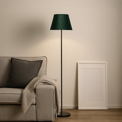 Dark green fabric shade floor lamp with slim black stand styled in modern living room beside grey sofa.