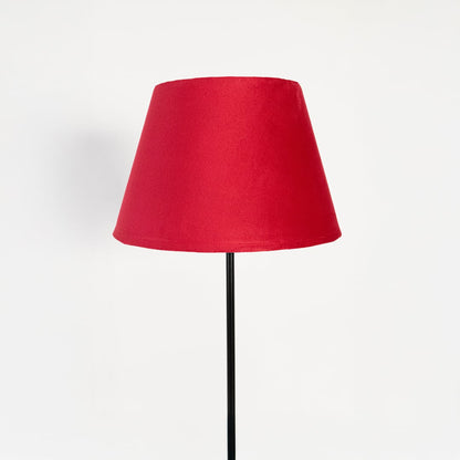 Closeup of elegant red fabric shade floor lamp with slim black metal stand for bedroom or living room lighting.