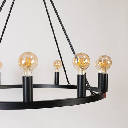 Detailed closeup of amber Edison globe bulbs with black metal cylindrical sockets on contemporary industrial chandelier frame.