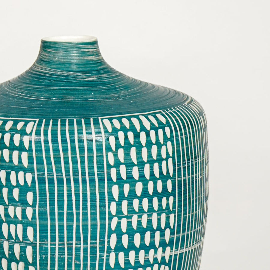 Closeup of teal glazed ceramic vase with white hand painted pattern showcasing textured finish for elegant home decor styling.