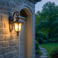 Vintage outdoor wall lantern in bronze metal with frosted glass glowing warmly at entrance for exterior lighting.