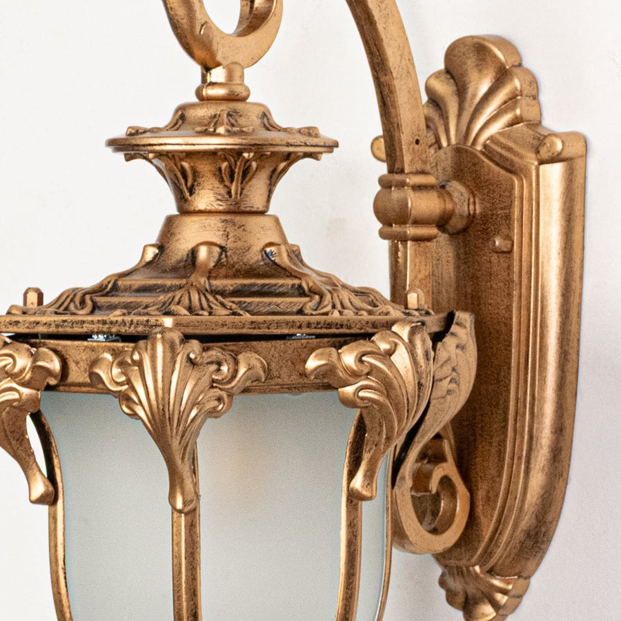 Closeup view of gold metal wall lantern highlighting ornate carvings frosted glass shade and premium finish quality.
